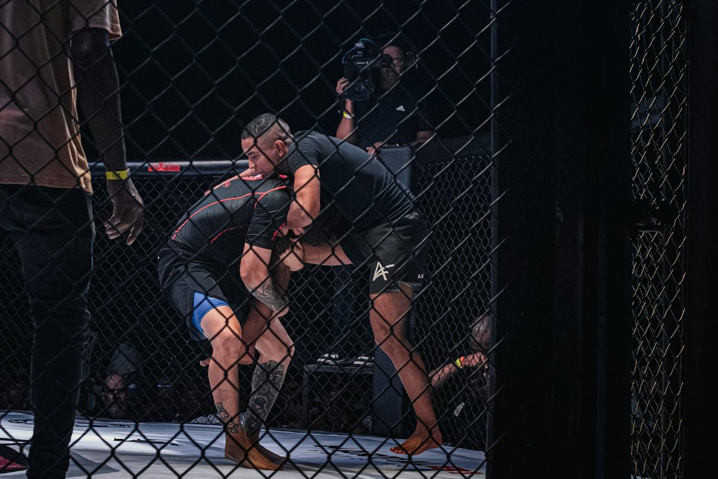 Two MMA fighters clinched against the cage